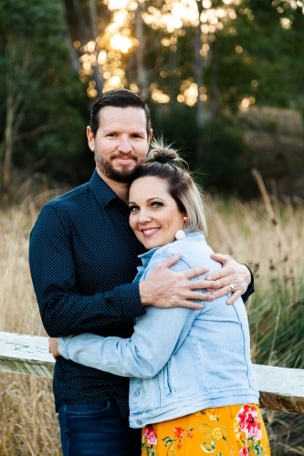 Married couple hug each other outside in park - Australian Stock Image