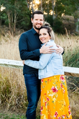 Married couple hug each other outside in park - Australian Stock Image