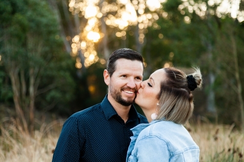 Married couple wife kisses husband in park - Australian Stock Image