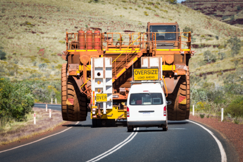Massive mining truck escorted by pilot vehicle on a remote highway. - Australian Stock Image