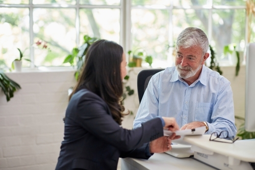 Mature aged male office worker meeting with a woman in a creative warehouse space - Australian Stock Image