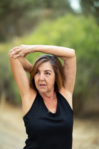 Mature woman doing arm and shoulder stretching exercises - Australian Stock Image