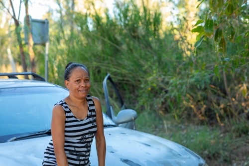 mature woman leaning on car bonnet on roadside - Australian Stock Image
