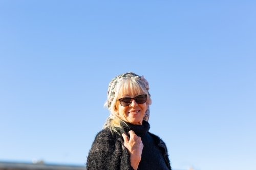 mature woman wearing sunglasses photographed against a blue sky
