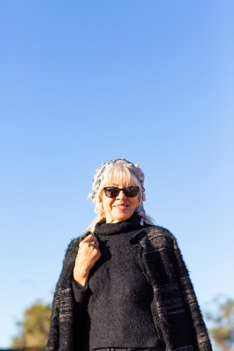 mature woman wearing sunglasses photographed against a blue sky - Australian Stock Image