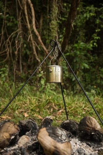 Metal pot hanging on a tripod over the fire pit. - Australian Stock Image