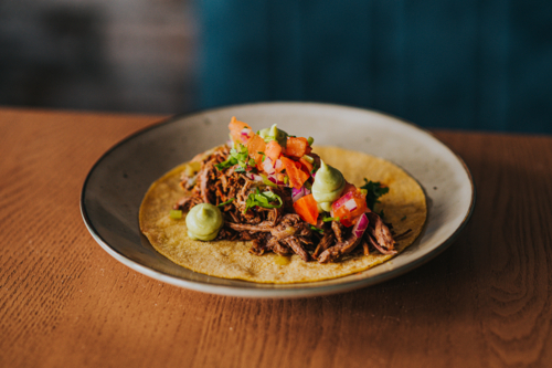 Mexican Taco With pulled Meat, Fresh Toppings, and Guacamole on Rustic Wooden Table - Australian Stock Image
