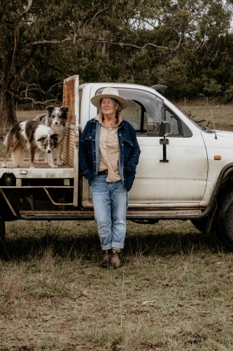 Mid fifties woman with eyes closed stands next to ute on the farm. - Australian Stock Image
