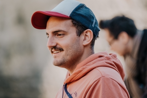 Mid twenties man in a cap smiles. - Australian Stock Image