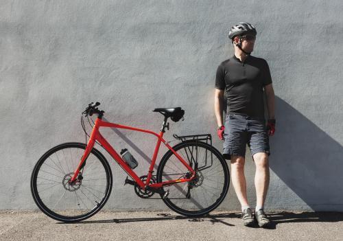 Middle aged cyclist man standing next to his bike with helmet on - Australian Stock Image