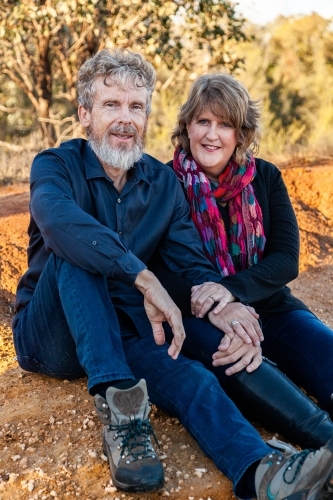 Middle aged husband and wife sitting together outside - Australian Stock Image