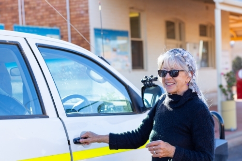 Middle-aged lady opening door on vehicle - Australian Stock Image