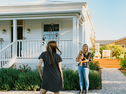Middle-aged woman holding a dog outside with teenage girl back view. - Australian Stock Image