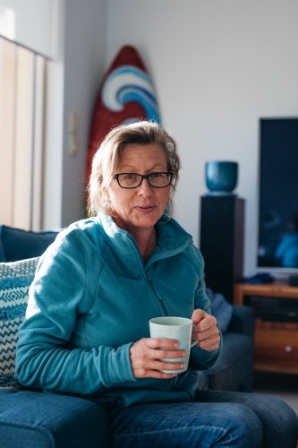 Middle aged woman looking happy with mug in hand