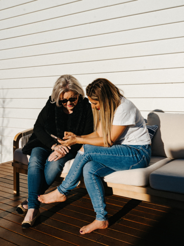 Middle aged woman showing an elderly person a mobile device - Australian Stock Image