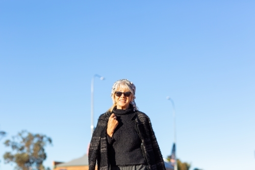 middle-aged woman wearing black against blue sky - Australian Stock Image