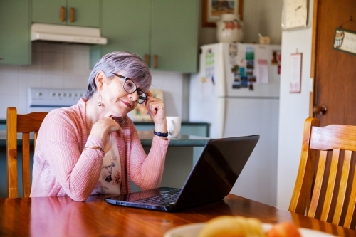 Middle aged woman working on laptop from home - Australian Stock Image