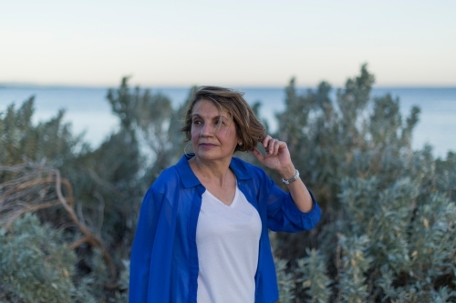 Middle eastern woman walking on shoreline at dusk - Australian Stock Image