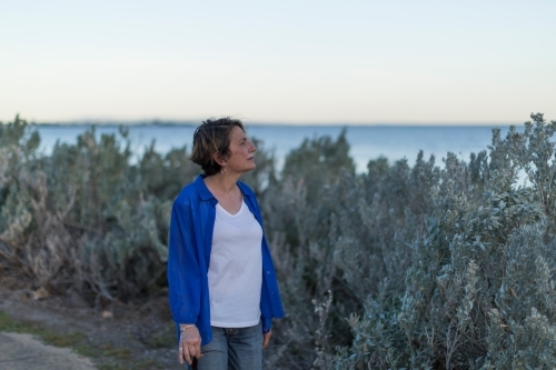 Middle eastern woman walking on shoreline at dusk - Australian Stock Image