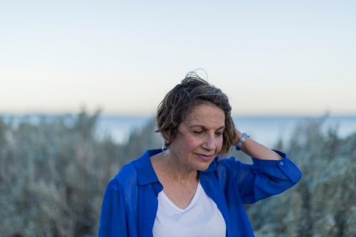 Middle eastern woman walking on shoreline at dusk - Australian Stock Image