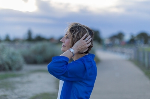 Middle eastern woman walking on shoreline at dusk - Australian Stock Image