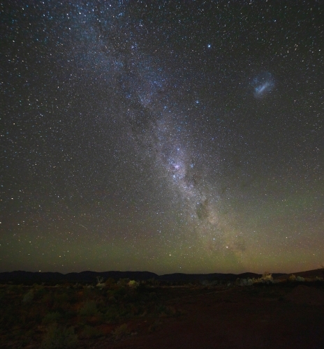 Miky Way and Magellanic Cloud over remote landscape - Australian Stock Image