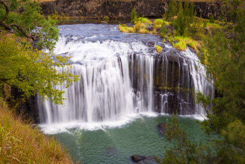 Millstream Falls cascading into a turquoise pool surrounded by lush greenery. - Australian Stock Image