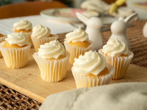 Mini cupcakes with white icing on wooden board with easter table decorations - Australian Stock Image