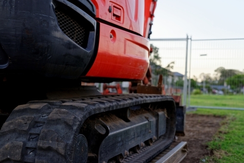 Mini digger standing idle at a construction site - red excavator - Australian Stock Image