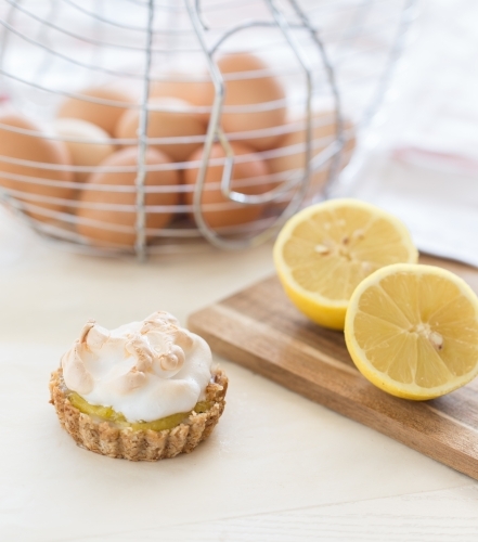 Mini Lemon Meringue Tarts with Lemons and board - Australian Stock Image