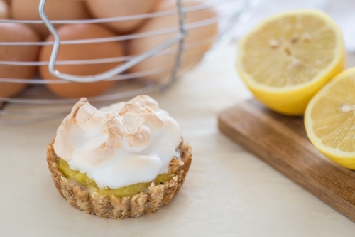 Mini Lemon Meringue Tarts with Lemons and board - Australian Stock Image