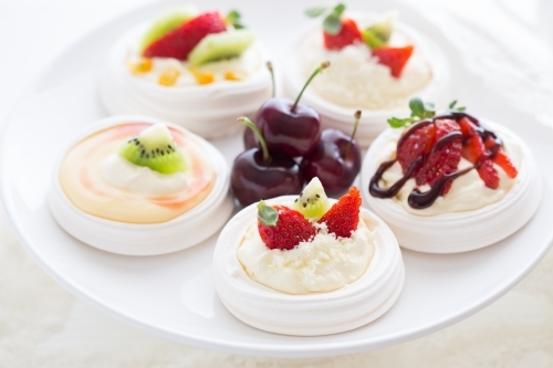 Mini Pavlova desserts topped with fruit on a white plate - Australian Stock Image