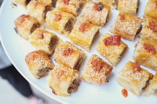 Mini sausage rolls on white serving plate - Australian Stock Image