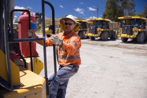 Mining operator man holding on the handrails while climbing up the dump truck - Australian Stock Image