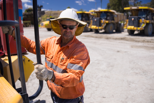 Mining operator man holding on the handrails while climbing up the dump truck - Australian Stock Image