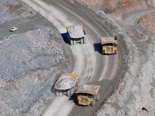 Mining trucks moving along roadway of an open cut mine - Australian Stock Image