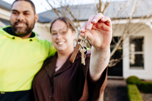 Mixed ethnicity couple showing keys of their new home - Australian Stock Image