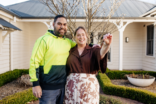 Mixed ethnicity couple showing keys of their new home - Australian Stock Image