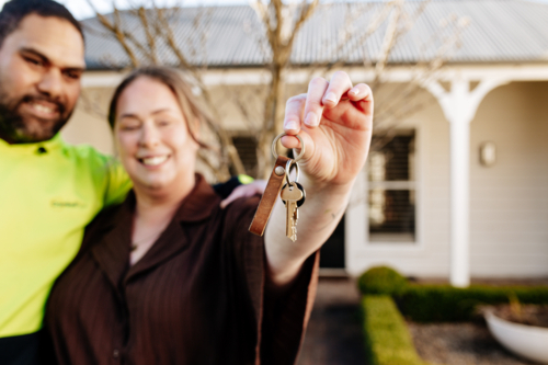 Mixed ethnicity couple showing keys of their new home - Australian Stock Image