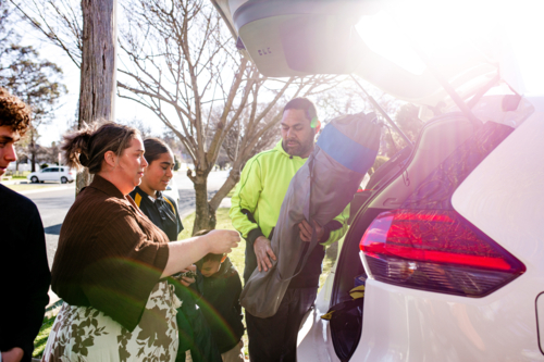Mixed ethnicity family unpacking car boot - Australian Stock Image