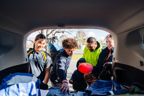 Mixed ethnicity family unpacking car boot - Australian Stock Image