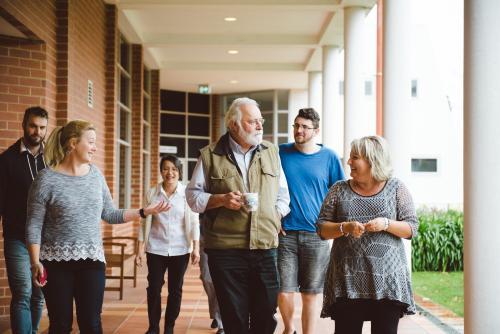 Mixed group of people walking along outside university building - Australian Stock Image