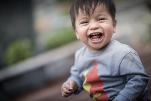 Mixed race 1 year old baby boy plays happily in his suburban backyard - Australian Stock Image