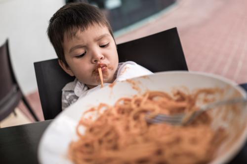Mixed race boy eating pasta at a suburban Italian restaurant - Australian Stock Image