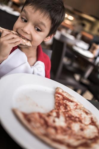 Mixed race boy eating pizza at a suburban Italian restaurant - Australian Stock Image