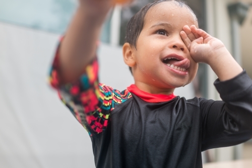 Mixed race boy playing in small backyard pool - Australian Stock Image