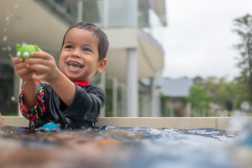 Mixed race boy playing in small backyard pool - Australian Stock Image