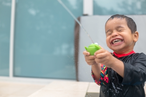 Mixed race boy playing in small backyard pool - Australian Stock Image