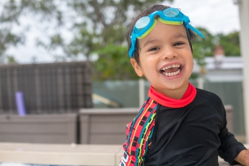 Mixed race boy playing in small backyard pool - Australian Stock Image
