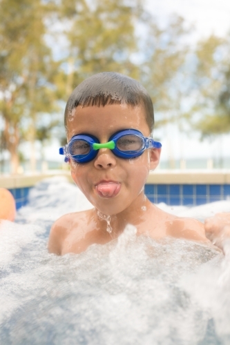 Mixed race boy swims and plays in a backyard pool - Australian Stock Image